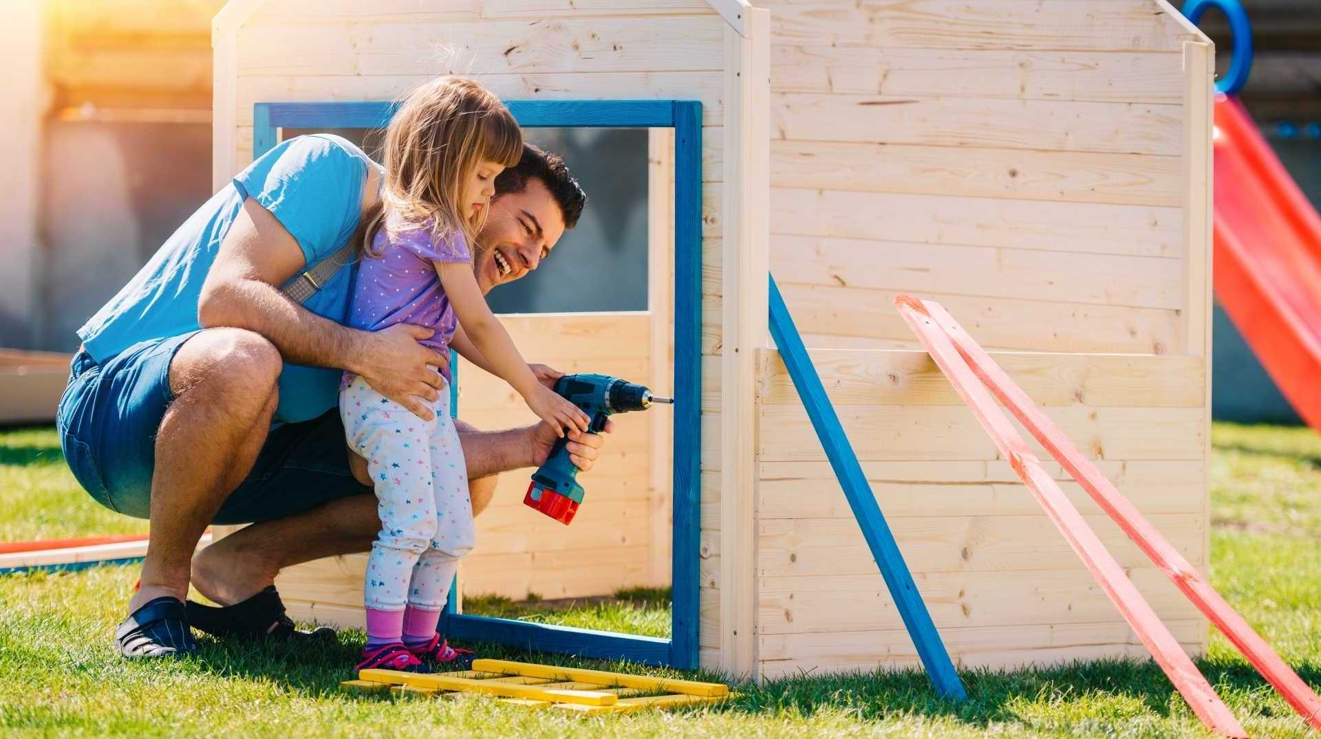 Vater und Tochter bauen gemeinsam ein Garten Spielhaus auf.