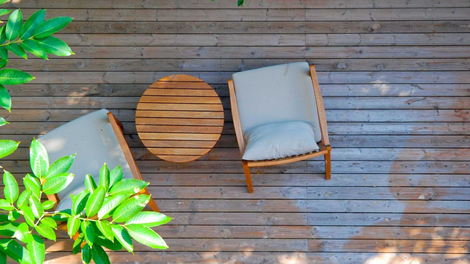 Vogelperspektivaufnahme von zwei Holzstühlen mit einem kleinen Beistelltisch auf einer Holzterrasse