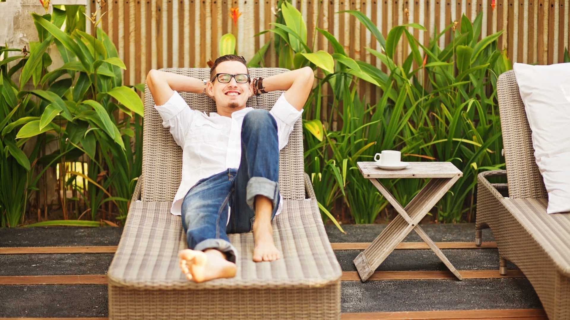 Mann liegt gemütlich auf seiner Sonnenliege aus Rattan