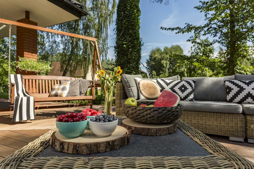 Verandaschaukel aus Holz neben Sitzgelegenheiten