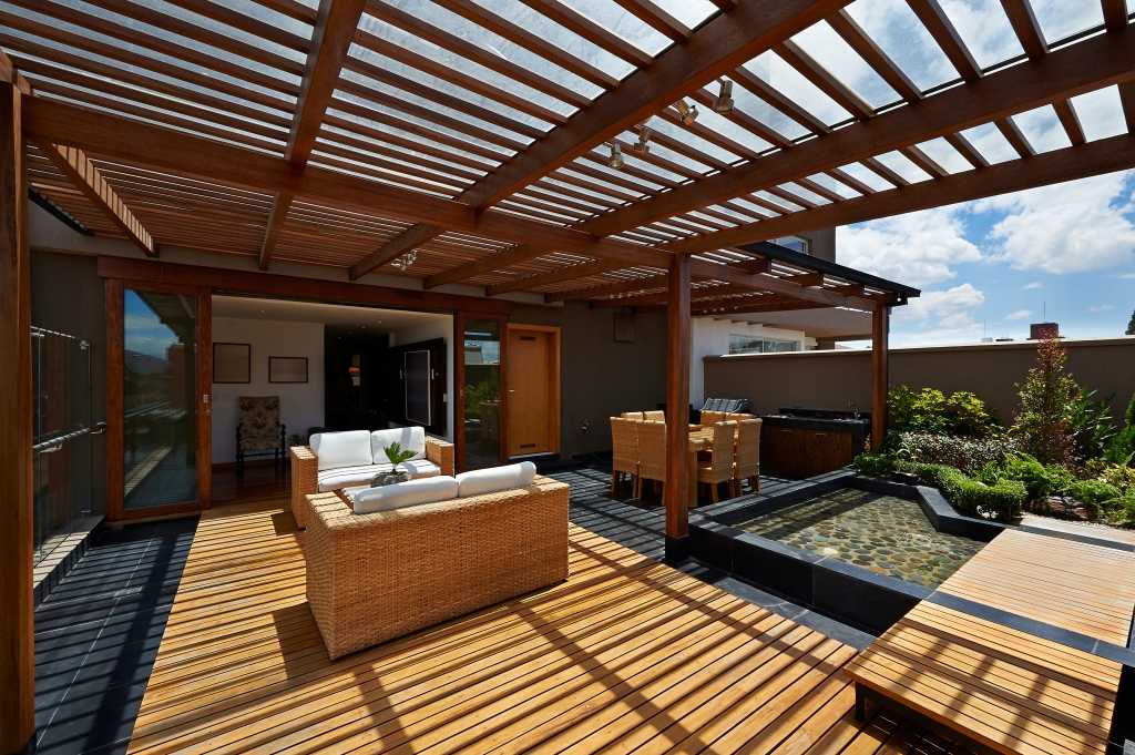 Terrassenmöbel inmitten einer wunderschönen Pergola mit Blick ins Haus.