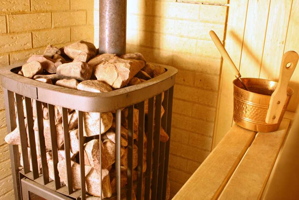 Holzofen im inneren einer Sauna mit Steinen gefüllt.