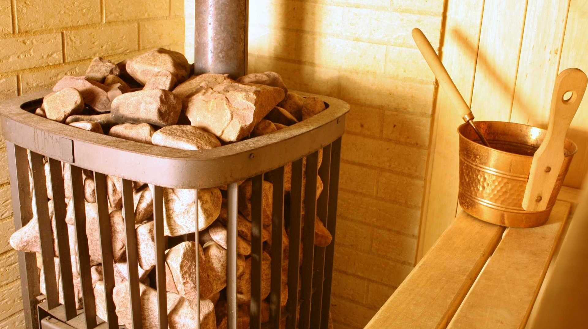 Holzofen im inneren einer Sauna mit Steinen gefüllt.