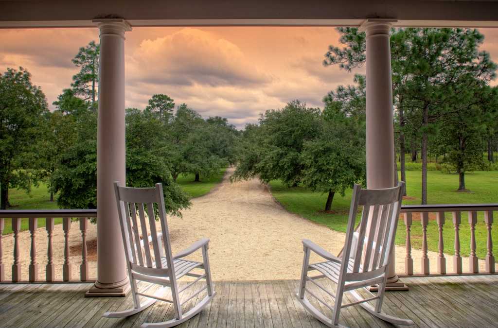 Schaukelstühle auf Veranda mit Blick in den Garten.