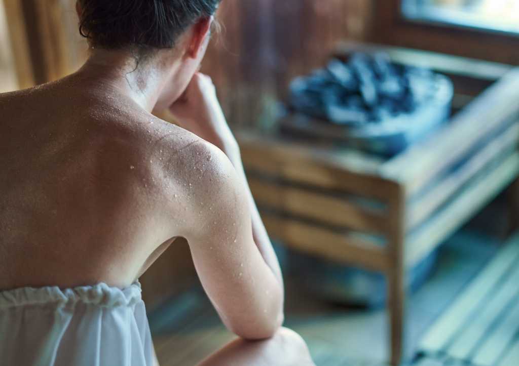 Frau sitzt schwitzend in der Sauna
