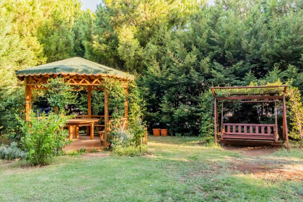 Idyllischer Garten mit einem Pavillon mit Stoffdach und einer überdachten Hollywood-Schaukel zum entspannen.