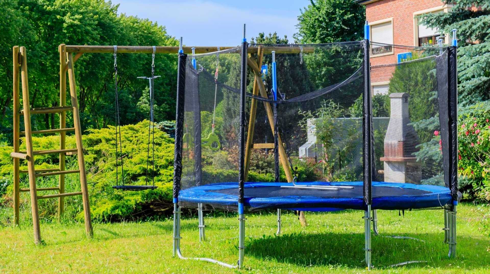 Trampolin im Garten vor einer Schaukel