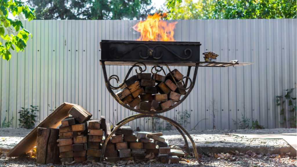 Grill indem ein Feuer brennt auf dem Boden liegt Holz