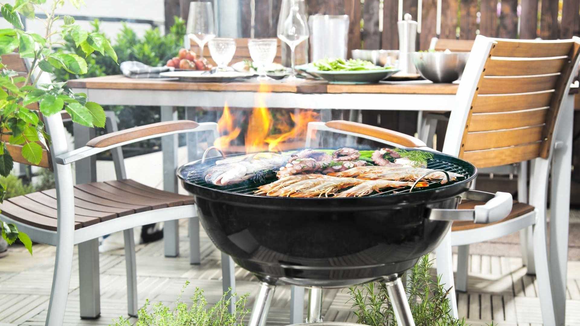 Gedeckter Gabentisch mit leckerem Grillgut auf dem Holzkohlengrill