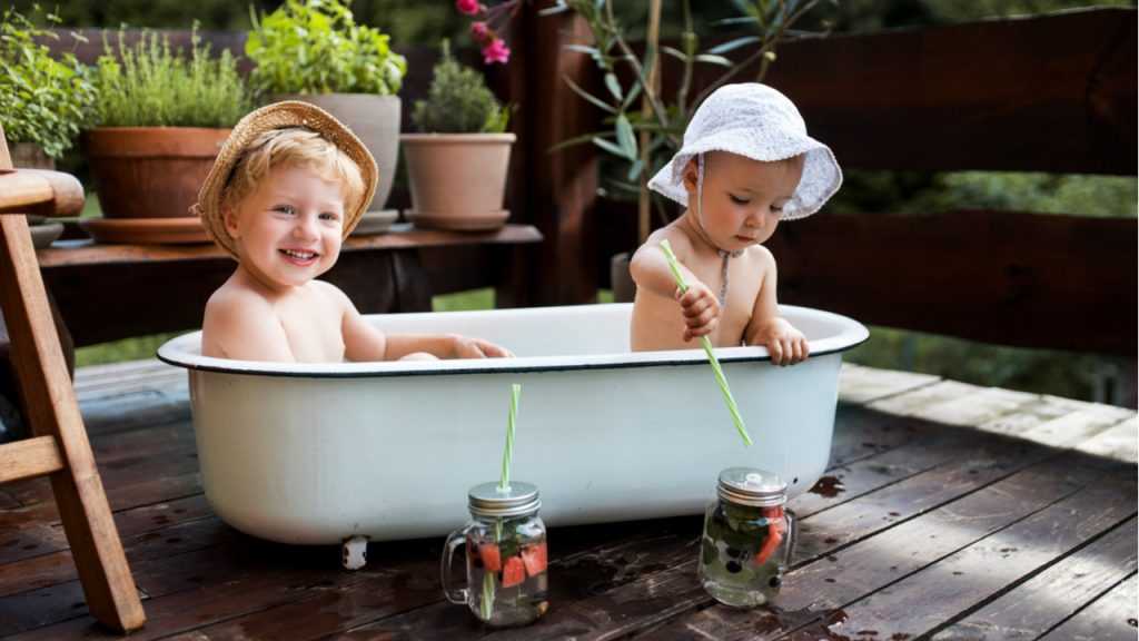 zwei kleine Kinder in einer Badewanne auf einer Terrasse