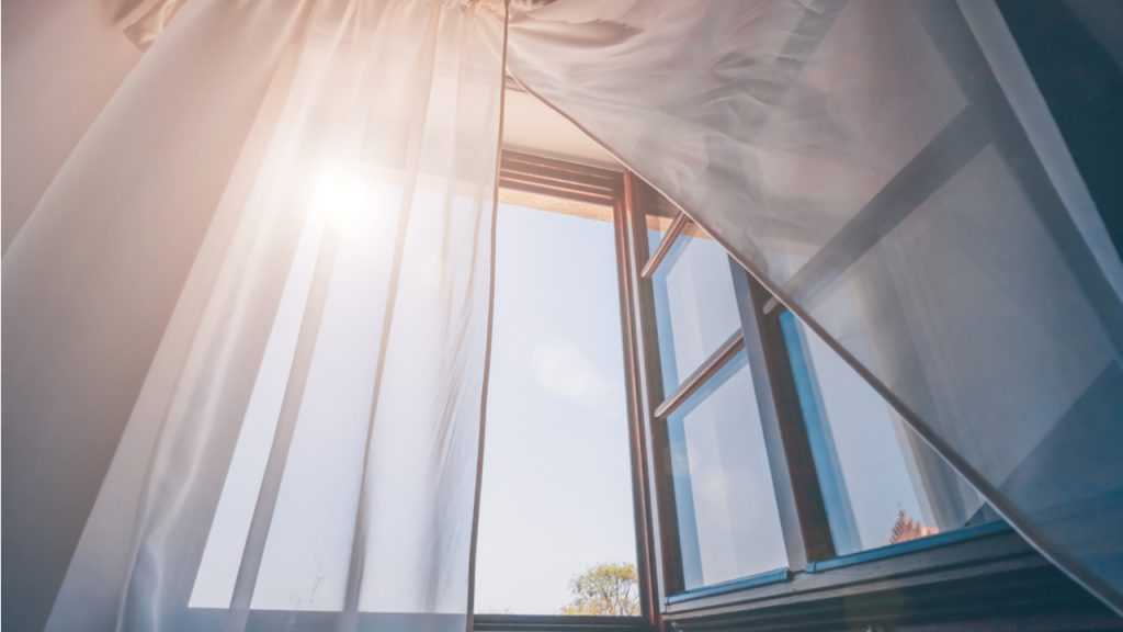 offenes Fenster mit Gardinen davor