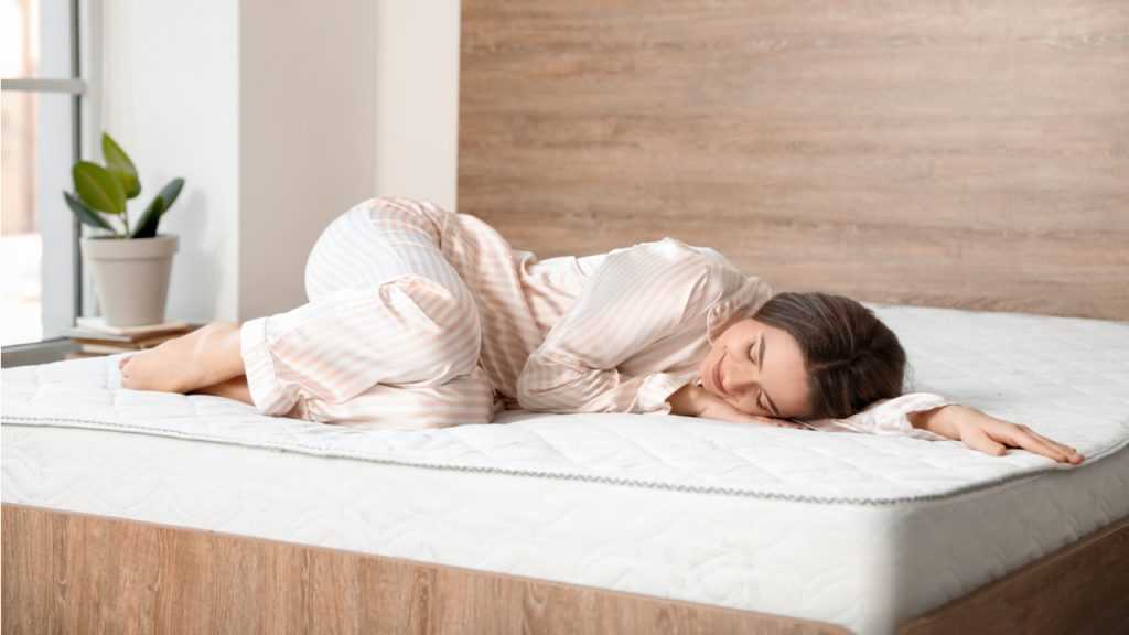 Frau die auf einer Matratze in einem Holz Bett liegt