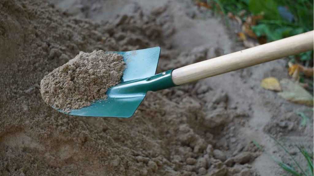 Schaufel mit Sand wird aufgehoben.