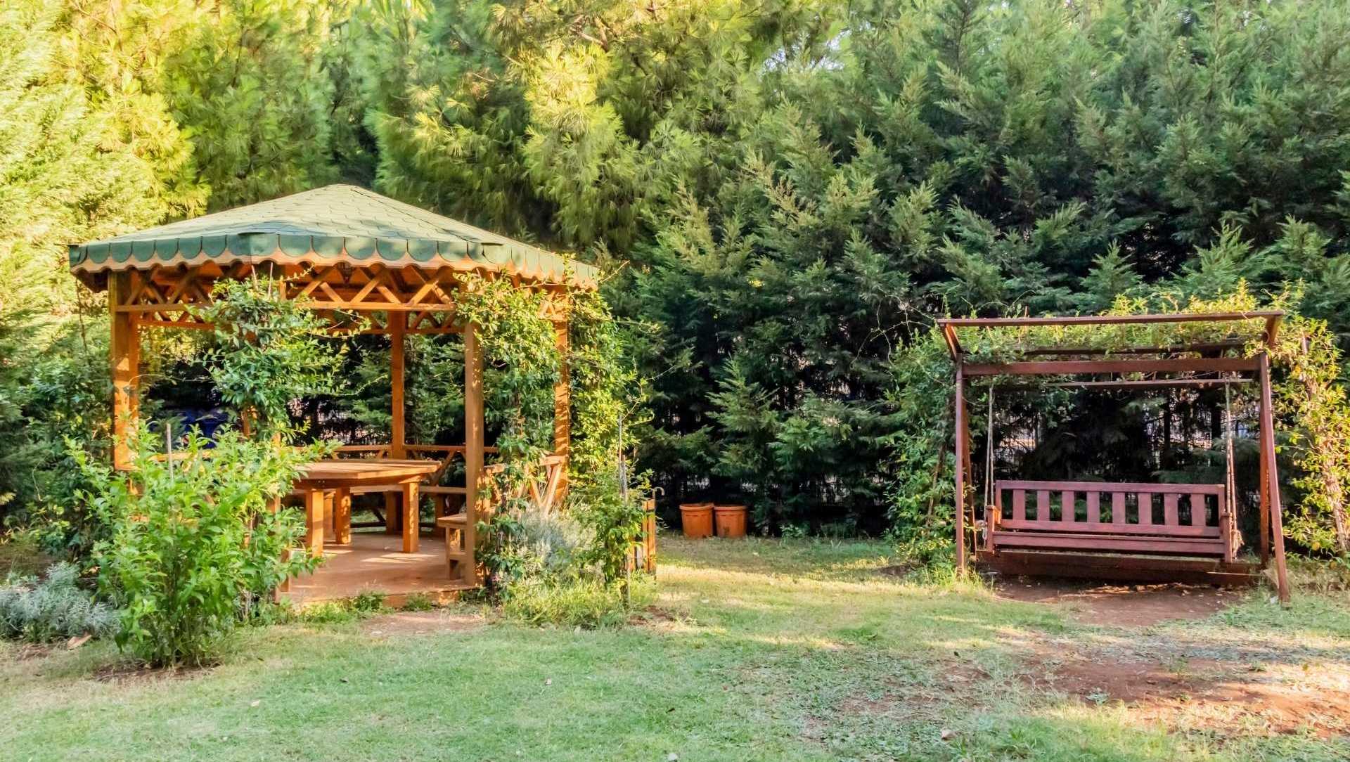 Idyllischer Garten mit einem Pavillon mit Stoffdach und einer überdachten Hollywood-Schaukel zum entspannen.